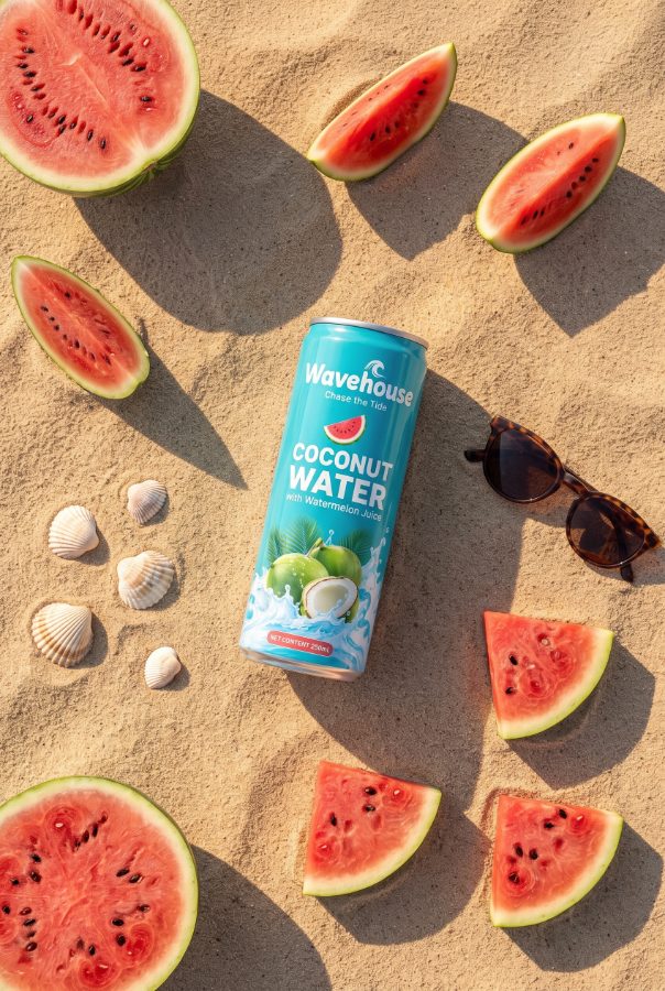 Beverage marketing visual for Wavehouse coconut water brand — flat lay on sand